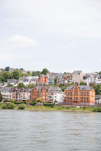 Buildings by river against sky