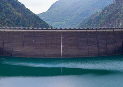 Scenic view of dam and mountains against sky