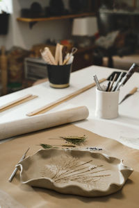 Clay handmade ceramic plates rolled on the table with plants and flowers. top view on handcrafted