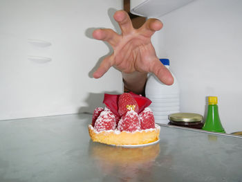 Close-up of hand reaching for dessert in refrigerator