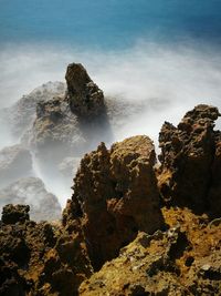 Scenic view of rocks in sea against sky