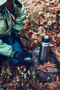 Woman with backpack having break during trip on autumn cold day drinking a hot drink from thermos