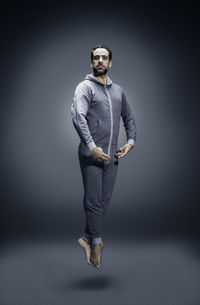 Full length portrait of man levitating against gray background