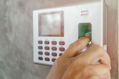 Close-up of hand holding camera against wall