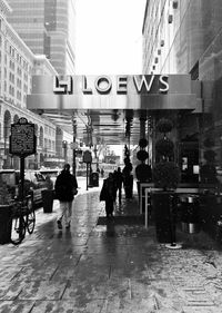 People walking on wet street in city during rainy season