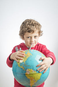 Portrait of boy holding camera over white background