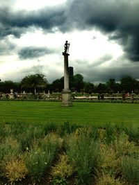 Statue on field against cloudy sky