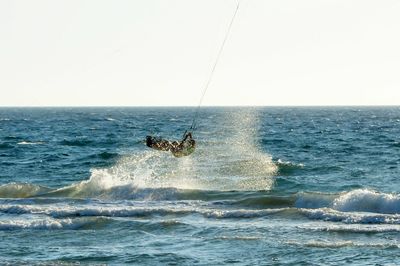 Man surfing in sea against clear sky