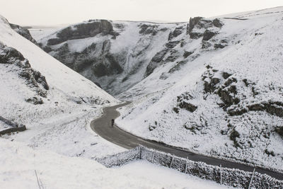 Road amidst snowcapped mountains against sky