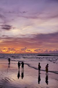 People on beach against dramatic sky