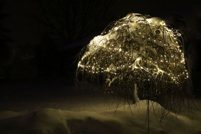 Close-up of illuminated lights against sky at night
