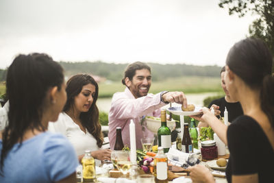 Male and female friends enjoying dinner during party in backyard