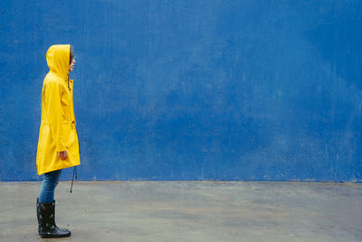Side view of woman standing against blue wall