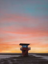 Lifeguard hut on beach against sky during sunset