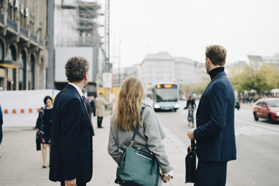 Businesswoman with male coworkers standing in city