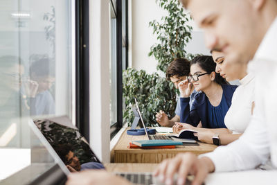 Business people working together sitting by window at workplace