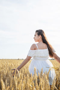 Portrait of smiling young woman standing against sky