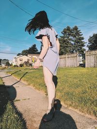 Full length of woman standing on footpath against sky