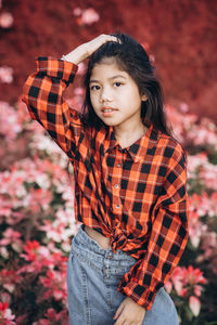 Portrait of cute girl standing against flowering plants outdoors