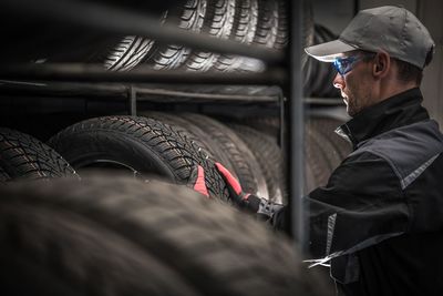 Male mechanic arranging tires on shelves in auto repair shop