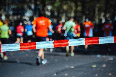 Cordon tape on road with people running in background during marathon