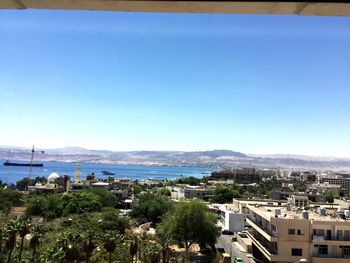 High angle view of city by sea against clear sky