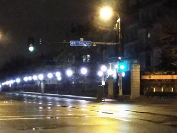 Empty road in illuminated city at night