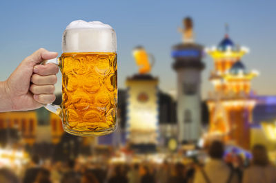 Close-up of hand holding beer glass against blurred background