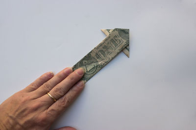Cropped hand of person holding knife against white background