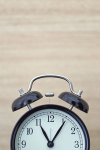 Close-up of alarm clock against wooden wall