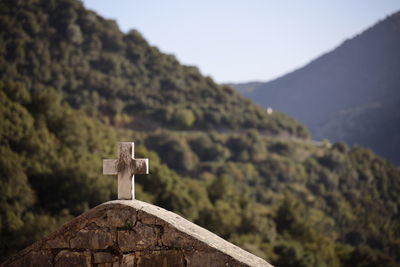 Low angle view of christian cross against mountain