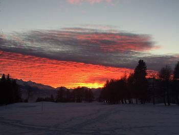 Scenic view of snow covered land against sky at sunset