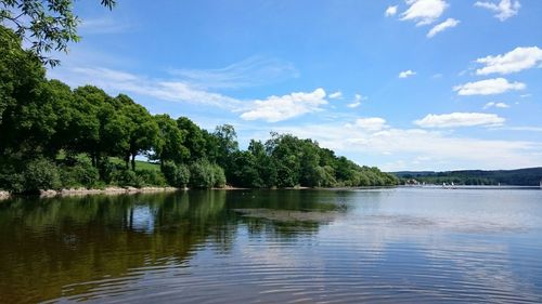 Scenic view of lake by trees against cloudy sky