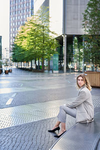 Portrait of young woman sitting in city