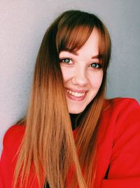 Close-up portrait of smiling young woman against wall