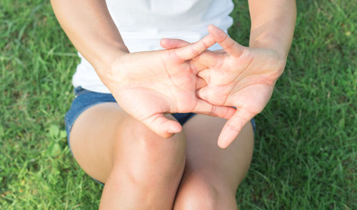 Low section of woman touching grass on field