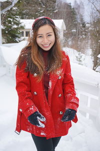 Portrait of smiling young woman standing in snow