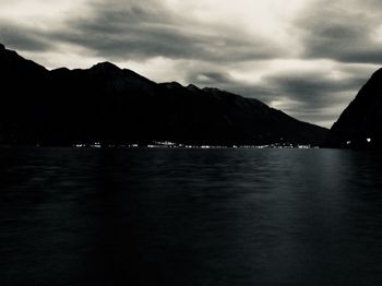 Scenic view of sea and silhouette mountains against sky at dusk