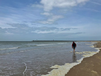 Rear view of man on beach against sky