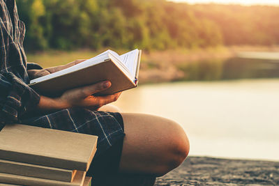 Midsection of man reading book while sitting on seat