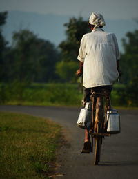 Rear view of man riding bicycle on road