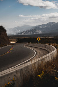 Road leading towards mountains against sky