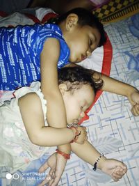 High angle view of siblings relaxing on bed