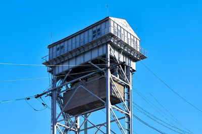 Low angle view of telephone pole against clear blue sky