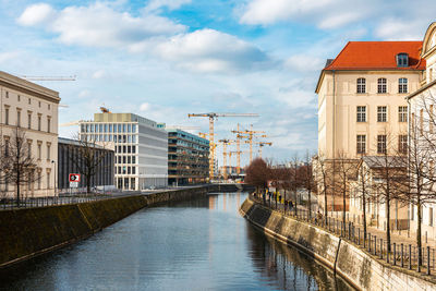 Bridge over canal amidst buildings in city against sky