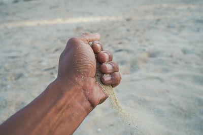 Close-up of person hand on sand