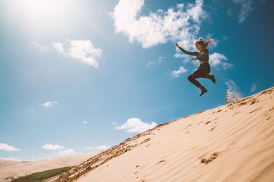 Low angle view of woman jumping in sky