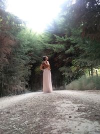 Woman standing on field against trees