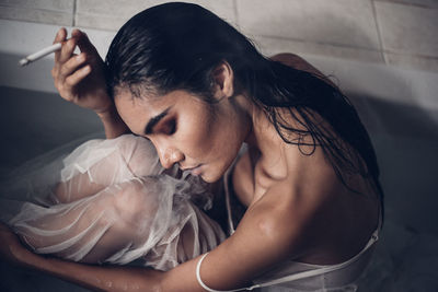 Seductive woman smoking cigarette in bathtub