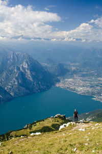 Man standing on mountain by lake against sky